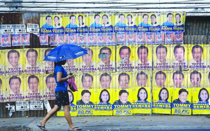 A women passes by campaign posters in this photo dated March 4, 2019. JACOB MAENTZ