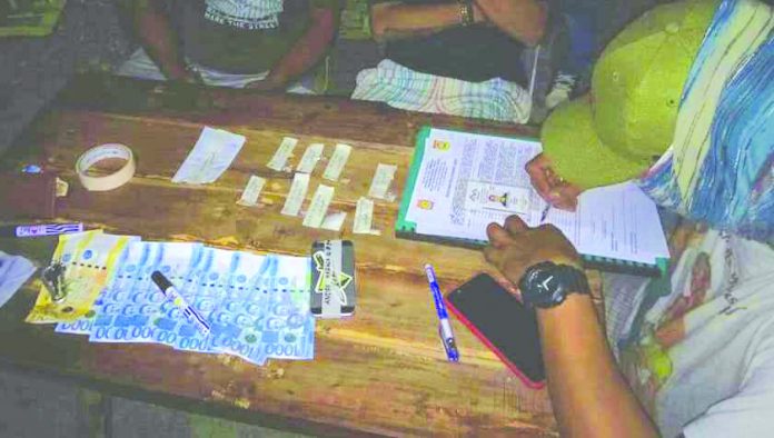 An antidrug personnel examines the suspected shabu and drug paraphernalia seized from Andre Mabasa after he sold illegal drugs to a poseur-buyer in Kalibo, Aklan on June 27. PDEA REGION 6