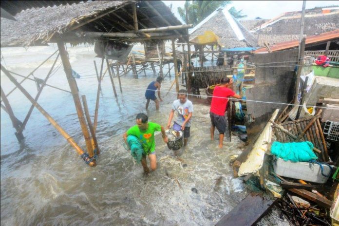 These residents of the coastal barangay Sto. Niño Sur, Arevalo, Iloilo City salvage whatever things they can from their houses that are being battered by big waves. IAN PAUL CORDERO/PN