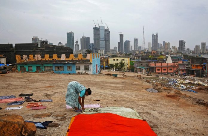 A woman puts clothes to dry overlooking central Mumbai's financial district skyline, India, June 18, 2019. REUTERS