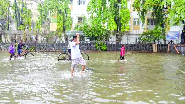 An Indian man carries a suitcase on his head as walks along a waterlogged street in Mumbai on Jul 2, 2019, following heavy monsoon rains. Mumbai was lashed by heavy rains for a second consecutive day, bringing the city to a virtual standstill. AFP