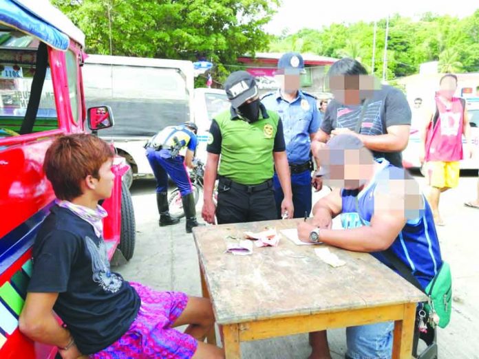 Drug suspect John Alfred Lacson sits handcuffed after police officers caught him in an entrapment operation in Barangay Rizal, Jordan, Guimaras on Tuesday, July 9. PDEA REGION 6