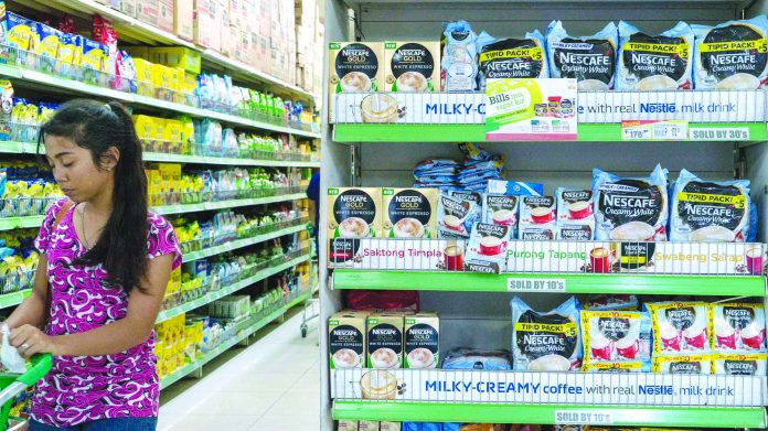 A Filipina consumer walks past an aisle of instant coffee at a grocery store in Metro Manila. AP