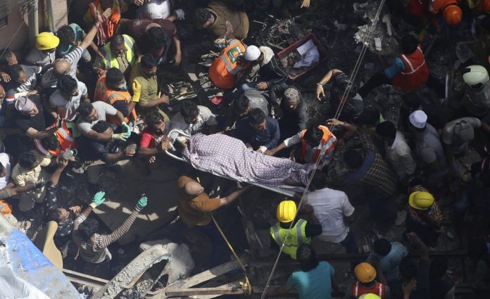 Rescuers carry the body of a victim at the site of a building that collapsed in Mumbai, India, Tuesday, July 16, 2019. A four-story residential building collapsed Tuesday in a crowded neighborhood in Mumbai, India's financial and entertainment capital, and several people were feared trapped in the rubble, an official said. AP