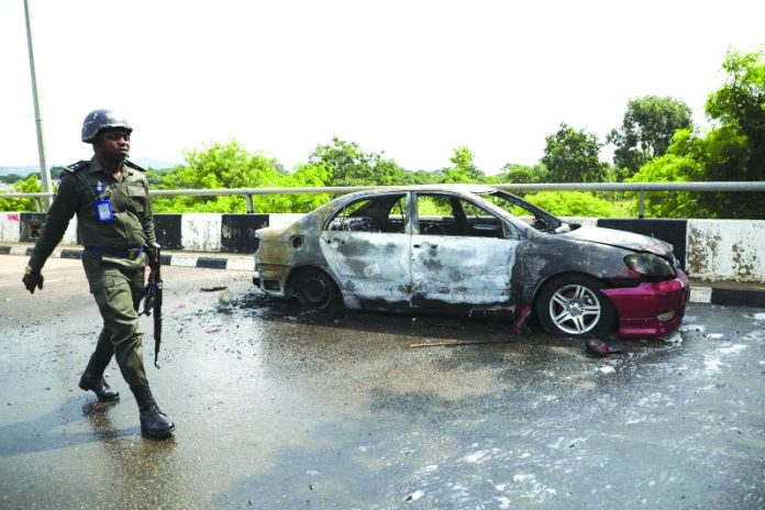 A policeman walks past a car burnt by supporters of an imprisoned leader of the Islamic Movement of Nigeria Ibrahim Zakzaky around the national assembly building in Nigeria's capital Abuja, on July 9. KOLA SULAIMON/AFP/GETTY IMAGES