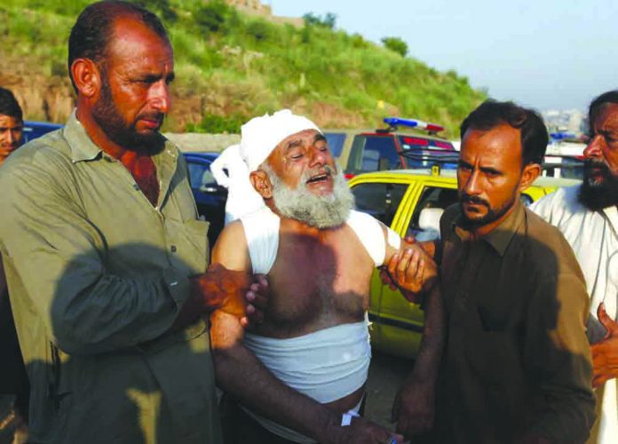 People help an injured victim who morns for the loss of his family member at the site of plane crash in Rawalpindi, Pakistan, Tuesday, July 30, 2019. AP