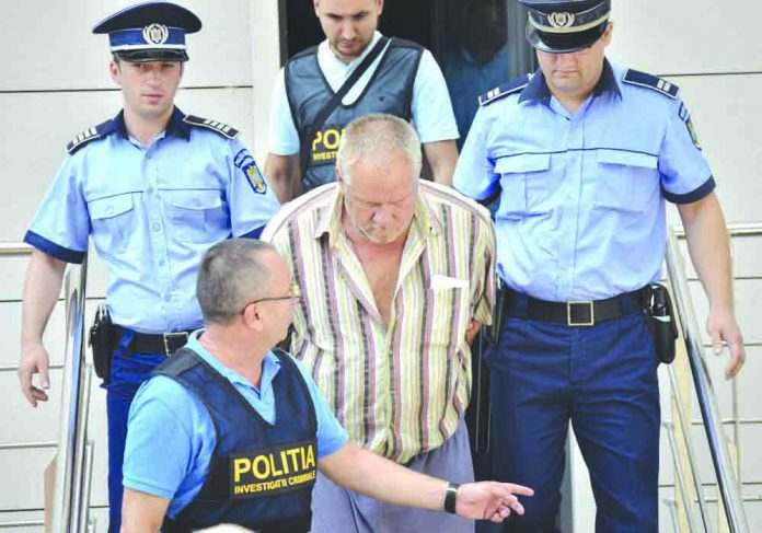 Police officers escort Gheorghe Dinca, the suspect in the case of rape and murder of a 15-year-old girl, from a court in Craiova, southern Romania, Saturday, July 27, 2019. AP