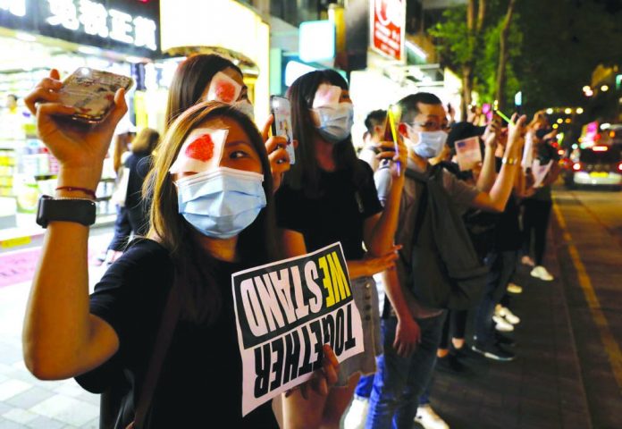 Demonstrators wear patches in remembrance of a woman who suffered an eye injury in a previous demonstration in Hong Kong, Friday, Aug. 23, 2019. AP