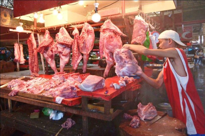 STILL SAFE. A vendor at the Iloilo Terminal Market inspects the meat and pork he is selling. They are safe, he insists. The deadly African swine fever virus has reached the country. IAN PAUL CORDERO/PN