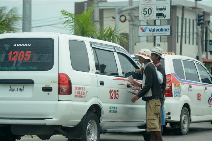 BEGGING FOR BENEVOLENCE. Two Badjao men beg for alms from this taxi stuck in traffic on Sen. Benigno Aquino Jr. Avenue in Mandurriao, Iloilo City. Begging and giving alms to beggars are punishable under City Regulation Ordinance 2002-400. IAN PAUL CORDERO/PN