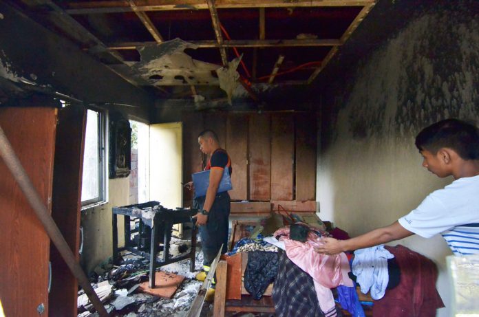 An officer of the Bureau of Fire Protection checks a house struck by fire in Barangay Cubay, Jaro district on Friday. IAN PAUL CORDER/PN