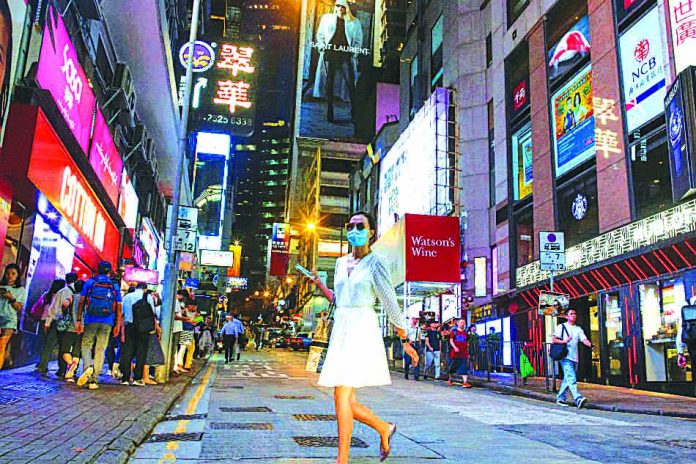 A woman crosses a street in the Central business district in Hong Kong, China Aug. 22, 2019. China plans to provide more support for its economy, including investing in infrastructure projects and regional development, while maintaining a prudent monetary policy. REUTERS