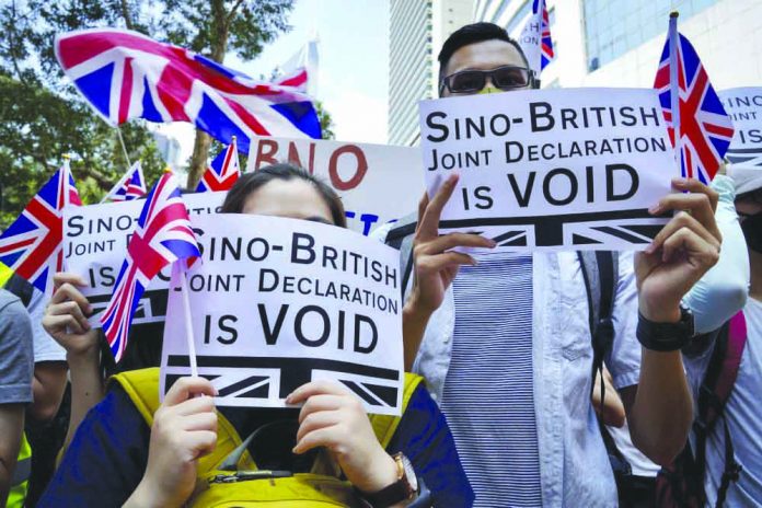 Protesters hold placards and wave British flags during a peaceful demonstration outside the British Consulate in Hong Kong, Sunday, Sept. 15, 2019. AP