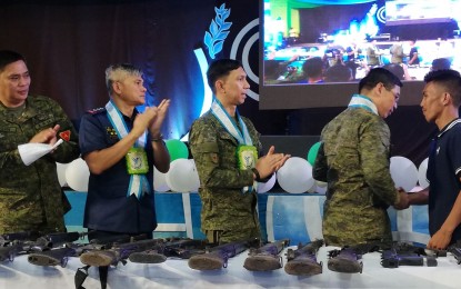 Army officials applaud the surrender of a firearm of former communist rebel ‘Ka Joros’ to Brigadier General Eric Vinoya (second from right) during the North Negros Peace Summit in Escalante City on Friday. NANETTE L. GUADALQUIVER/PNA