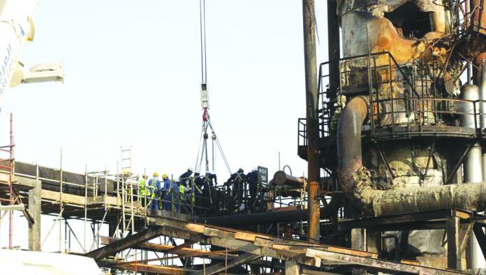 Workers repair a damaged refining tower at Saudi Aramco's Abqaiq crude oil processing plant following a drone attack in Abqaiq, Saudi Arabia last week. BLOOMBERG