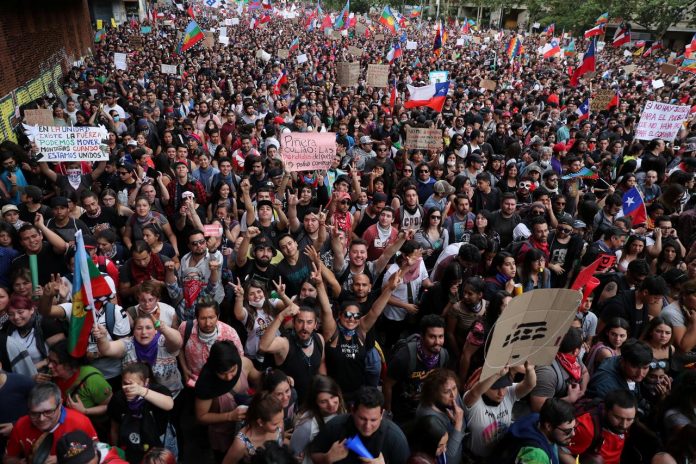 Demonstrators march with flags and signs during a protest against state economic model in Santiago, Chile on Oct. 25. REUTERS/IVAN ALVARADO