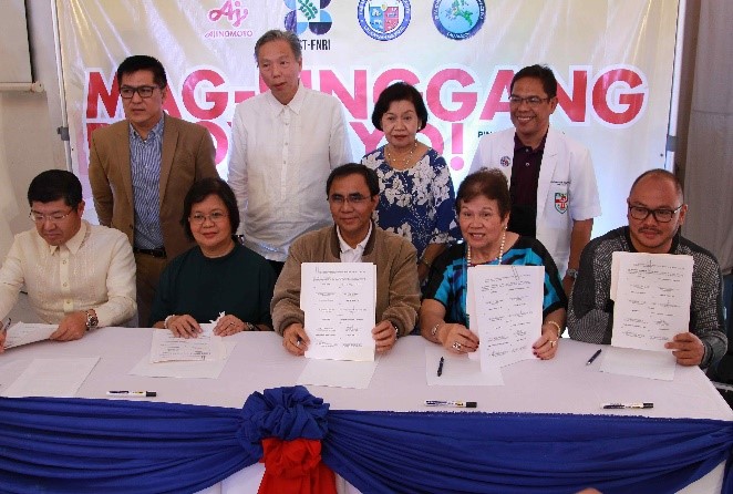 Contract signing participants (seated, from right) Cainta mayor Johnielle Kieth Nieto, Former DOH undersecretary and Mag -Pinggang-Pinoy® Tayo! 2019 Technical Working Group chairman Dr. Ethelyn Nieto, DOH CALABARZON division chief Dr. Noel Pasion, FNRI science research specialist Jovina Sandoval, and APC Group president Tsutomu Nara. Also present are Technical Working Group Committee members (standing, from right) Cainta Municipal Health Officer Dr. Edgardo Gonzaga, Nutritionist-Dietitian Fely Velandria, Ajinomoto director Andrew Ong and Health Marketing specialist Joevin Eusebio.