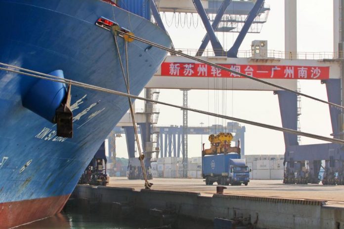 A crane lifts a container from a truck next to a cargo vessel at a port in Yantai, Shandong province, China Oct. 17. China’s economy expanded at its slowest rate in nearly three decades during the third quarter as it was hit by the long-running United States trade war and cooling domestic demand. REUTERS