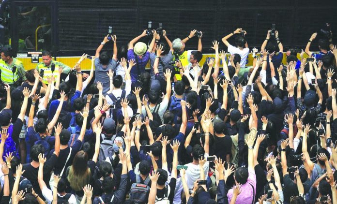 Supporters surround a police bus carrying political activist Edward Leung as it leaves the High Court in Hong Kong, Wednesday, Oct. 9, 2019. AP