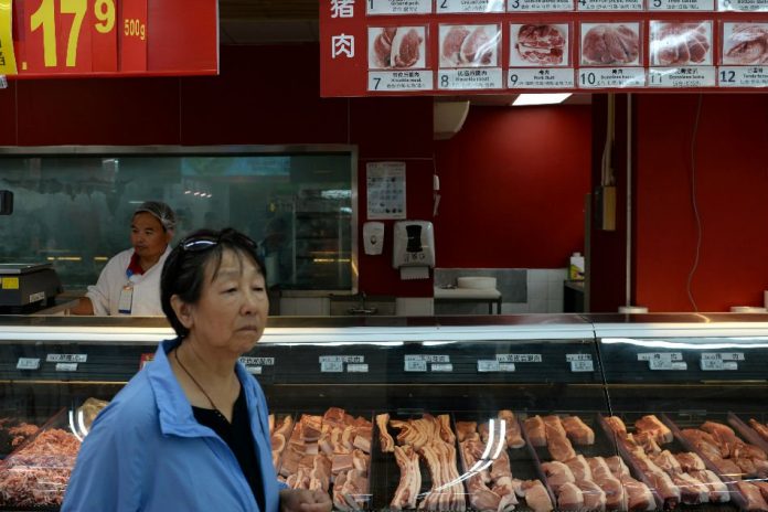 A woman walks past a pork counter at a Walmart in Beijing, China Sept. 23. TINGSHU WANG/REUTERS