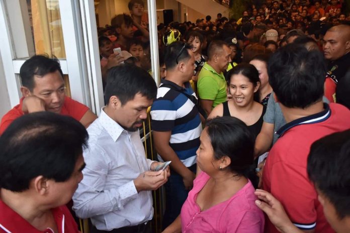 SHARING. Sen. Manny Pacquiao, accompanied by Bacolod City’s Mayor Evelio Leonardia and Cong. Greg Gasataya, shares his blessings to Bacolodnons by distributing financial assistance at the lobby of the Bacolod City Government Center on Oct. 17, 2019. BACOLOD CITY PIO