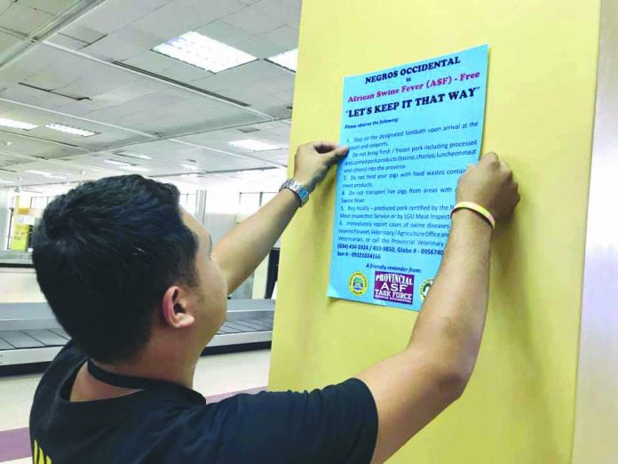 Personnel of the Negros Occidental Provincial African Swine Fever Task Force puts up posters at the Bacolod-Silay Aiport as part of its intensified move against the highly-contagious pig disease. NEGROS OCCIDENTAL PROVINCIAL ASF TASK FORCE