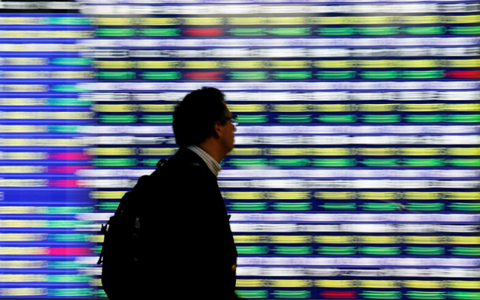 A man walks past an electronic stock quotation board outside a brokerage in Tokyo, Japan. Asian shares climbed on Wednesday and European stocks looked set for gains after the United States President Donald Trump said negotiators were close to inking an initial trade deal. TORU HANAI/REUTERS