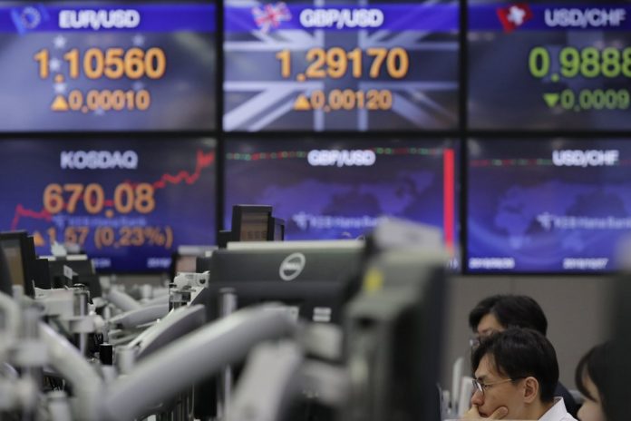 A currency trader gazes at computer monitors near screens showing the foreign exchange rates at the foreign exchange dealing room in Seoul, South Korea, Nov. 18. Asian shares are mixed Monday in a cautious mode after Wall Street closed out the week with milestones as the Dow Jones Industrial Average crossed 28,000 for the first time and the S&P 500 and Nasdaq hit record highs. LEE JIN-MAN/AP