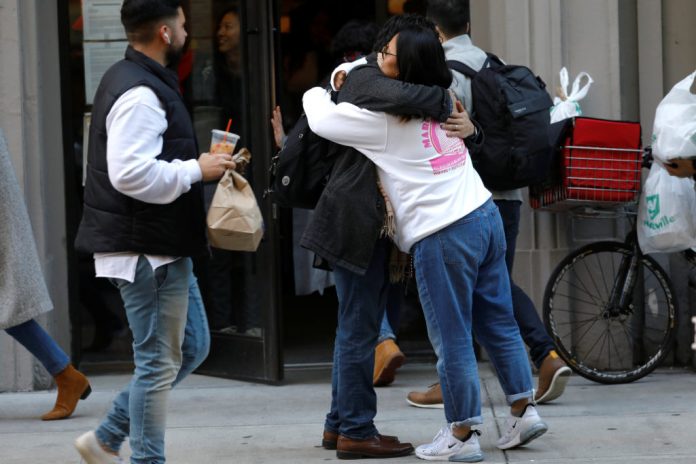 WeWork employees embrace on the sidewalk outside the entrance to the WeWork corporate headquarters in Manhattan, New York, U.S., November 21, 2019. MIKE SEGAR/REUTERS