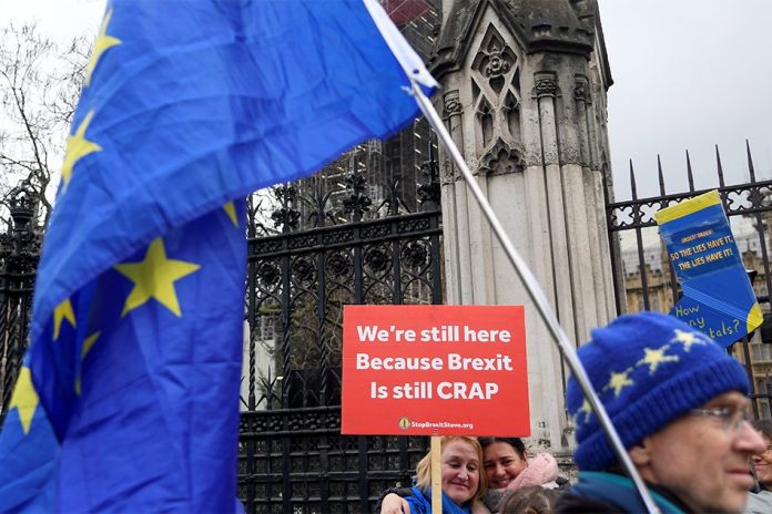 Anti-Brexit demonstrators hold signs outside the Houses of Parliament in London, Britain, Dec. 17, 2019. REUTERS