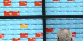 A man looks at an electronic stock board of a securities firm in Tokyo, Dec. 30, 2019. Asian shares were mostly lower Monday as investors awaited updates on the signing of a trade deal between the United States and China and kept a wary eye on North Korea. AP