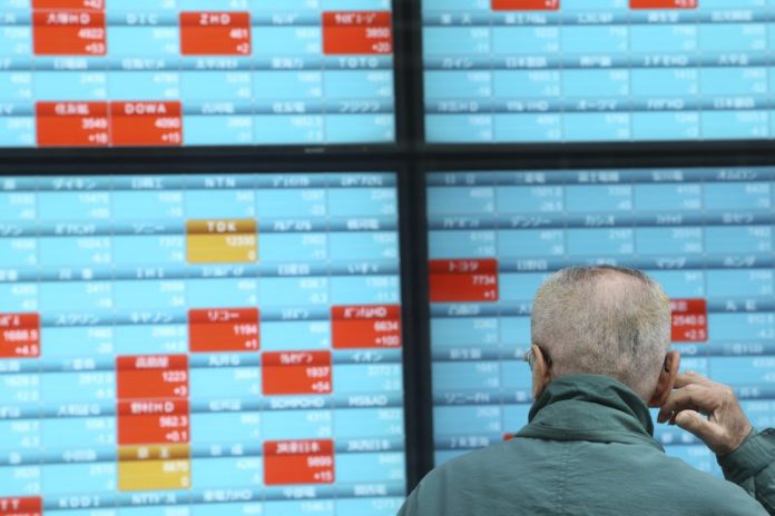 A man looks at an electronic stock board of a securities firm in Tokyo, Dec. 30, 2019. Asian shares were mostly lower Monday as investors awaited updates on the signing of a trade deal between the United States and China and kept a wary eye on North Korea. AP