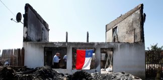 A Chilean flag hangs off the remains of a house after it was destroyed by fire in Valparaiso, Chile on Dec. 26. REUTERS/RODRIGO GARRIDO