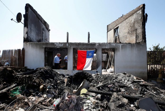 A Chilean flag hangs off the remains of a house after it was destroyed by fire in Valparaiso, Chile on Dec. 26. REUTERS/RODRIGO GARRIDO