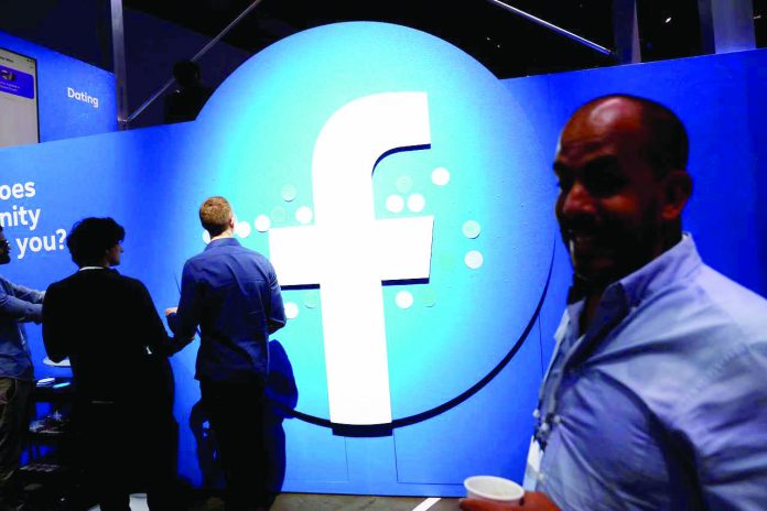 Attendees walk past a Facebook logo during Facebook Inc.’s F8 developers conference in San Jose, California, United States. Australia said on Thursday technology giants such as Facebook Inc. and Google will have to agree to new rules to ensure they do not abuse their market power and damage competition, or the government will impose new controls on them. REUTERS