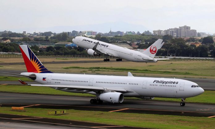 A Japan Airlines Boeing 767-300ER plane takes off as a Philippine Airlines Airbus A330-300 plane taxis on the runway of the Ninoy Aquino International Airport terminal 1 in Pasay city, metro Manila, Philippines. REUTERS