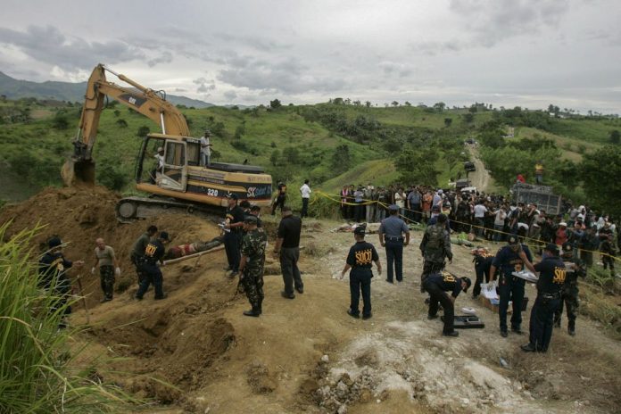 Relatives wait as police recover dead bodies along a hillside grave in Ampatuan municipality, Maguindanao province, southern Philippines, November 24, 2009. AP