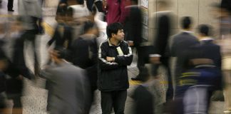 People walk past a man outside Shinjuku train station in Tokyo. REUTERS