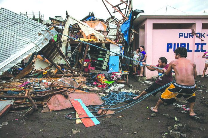 Workers repair damaged houses along the coastline in the aftermath of Typhoon Tisoy in Legazpi City, Albay on Tuesday. Tisoy brought heavy rains and strong winds as it made its first landfall on Monday evening in Sorsogon province. BASILIO SEPE/GREENPEACE