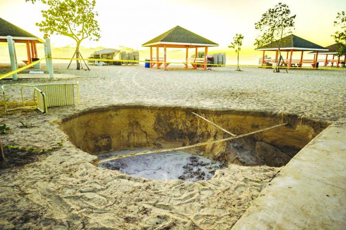 A sinkhole is surrounded by police tape after it appeared when a powerful magnitude 7.7 earthquake struck in the Caribbean Sea between Jamaica and eastern Cuba, at Public Beach on West Bay, Grand Cayman on Jan. 28, 2020. AP