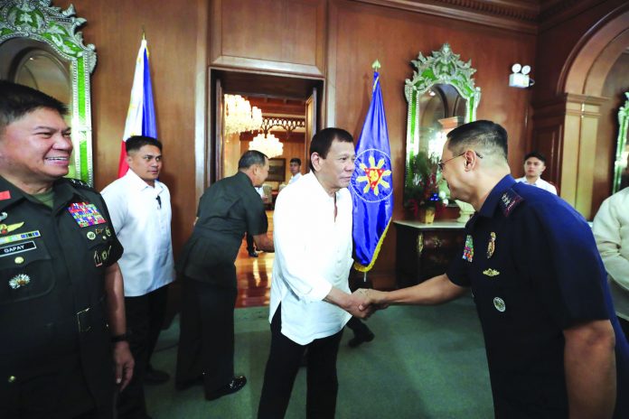 President Rodrigo Duterte (center) greets security officials at the Malacañang Palace on Monday. Duterte has ordered the military to prepare to deploy its aircraft and ships "at any moment's notice" to evacuate thousands of Filipino workers in Iraq and Iran should hostilities erupt there. PCOO