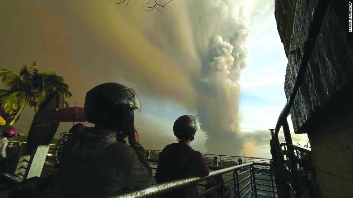 People watch from Tagaytay as plumes of smoke and ash rise from Taal Volcano on Jan. 12. The Philippine Institute of Volcanology and Seismology said “hazardous explosive eruption” is still imminent in the locality. AARON FAVILA/AP/CNN.COM