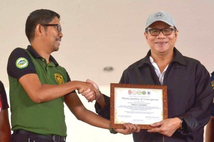 Director Alex Tablate (left) of the Philippine Drug Enforcement Agency in Western Visayas gives a certificate to Mayor Raul Banias attesting that Concepcion, Iloilo has been cleared of illegal drugs. Concepcion is the first town in northern Iloilo to be declared as drug-cleared. The declaration was made on Feb. 19, 2020. IAN PAUL CORDERO/PN