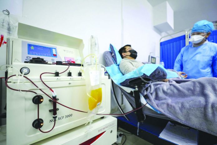 Dr. Kong Yuefeng, a recovered COVID-19 patient who has passed his 14-day quarantine, donates plasma in the city's blood center in Wuhan in central China's Hubei province on Feb. 18, 2020. CHINATOPIX/AP