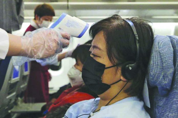 Stewardesses take temperatures of passengers as a preventive measure for the coronavirus on an Air China flight from Melbourne to Beijing before it land at Beijing Capital International Airport in China, Tuesday, Feb. 4, 2020. CHINATOPIX VIA AP