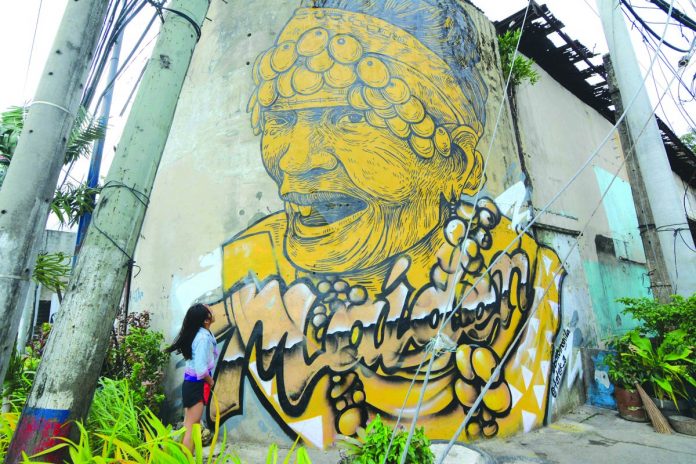 This Binukot mural – painted by local artists Archie Oclos and Dennis Bato – is an artwork of Rosita Caballero. She was the last known kept maidens of Panay Bukidnon. She died last July 2017 at the age of 73. Binukot is a tradition where a much selected women are kept hidden and are not allowed to be seen by any man until a certain age. IAN PAUL CORDERO/PN