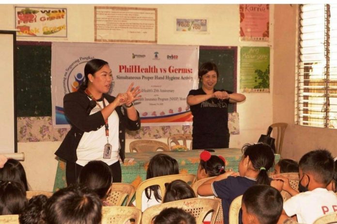 Atty. Valerie Anne H. Hollero, Acting RVP of Philhealth 6 shows the students of Andres Bonifacio Elementary School in Bacolod City the proper method on hand washing.