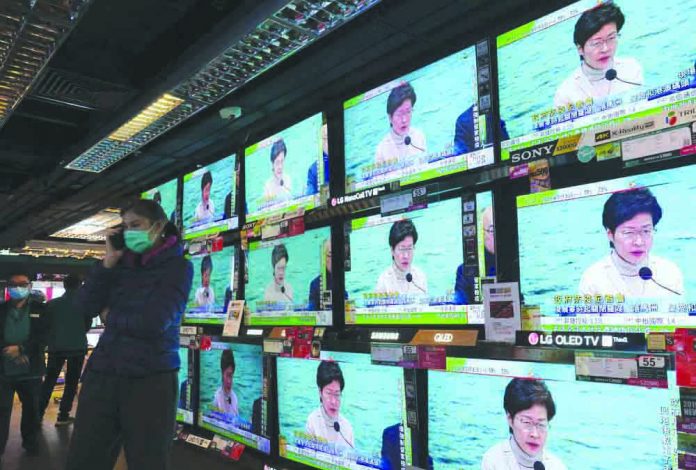 A man wears protective face masks stands in front of TV screens broadcasting Hong Kong Chief Executive Carrie Lam delivering a speech in Hong Kong, Monday, Feb. 3, 2020. AP