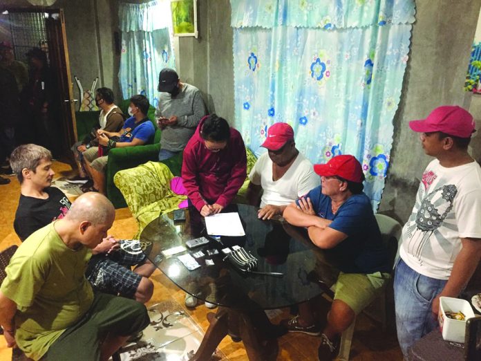 Antidrug operatives inspect items seized from George Bindol and Jared Villar. They were nabbed in an entrapment operation in Barangay Banago, Bacolod City on Feb. 22. CDEU/BCPO