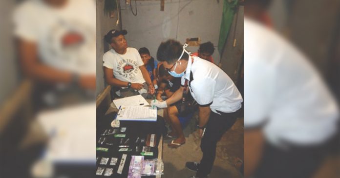 An antidrug officer inspect items seized from Bobby Palomo; Erikson Cordova, John Paul Guzon; Kube Salaza; and Jonathan Salcedo, who were nabbed in an entrapment operation in Barangay 8 Bacolod City on March 23. POLICE STATION 2/BCPO